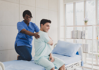 Patient caucasian man with woman nurse black people carer physical therapist two person sitting talk helping support give advice and holding relax massage on back body in room service hospital clinic