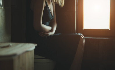 Unrecognizable woman on the toilet with stomach pain.