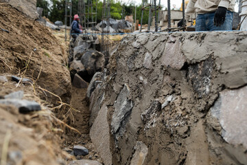 Stone foundations of a building, in the background a Latin bricklayer working, construction system known as 'mamposteria' in Mexico 