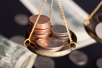 Close-up of gold coins on brass scales, importance and weight of money