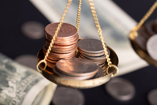 Close-up of gold coins on brass scales, importance and weight of money - Powered by Adobe