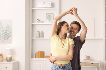 Happy young couple dancing together at home. Space for text