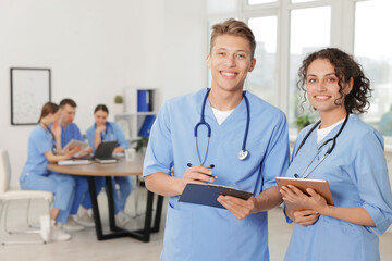 Medical students in uniforms studying together indoors, selective focus