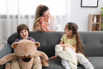 Children and their mother playing with different toys on sofa at home