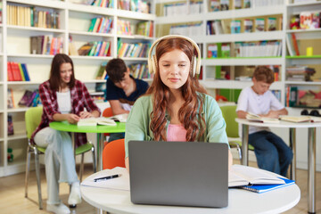 Student with laptop studying at table in library