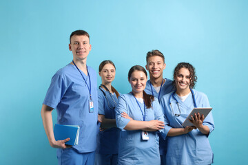 Group of medical students with tablet on light blue background