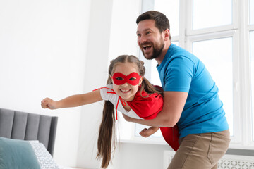 Father and his daughter in superhero costume playing at home