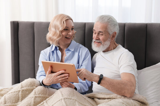 Senior man and mature woman with tablet spending time together at home. Happy couple