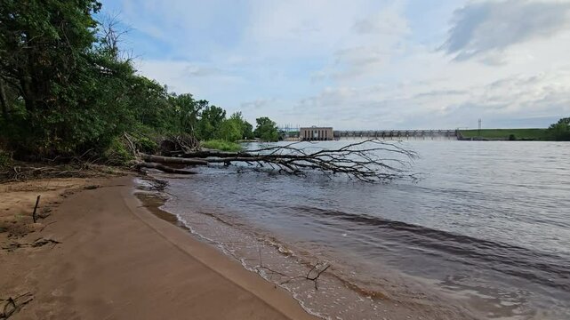 Wide angle shot and panning left to right of hydroelectricity dam on Wisconsin river with all spillways partiality opened after heavy rains