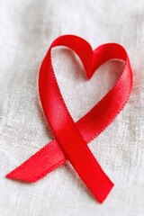 Red ribbon forming heart shape lying on white cloth background