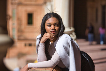 Portrait of young, beautiful, African woman, wearing leather jacket and shorts, with her hand on...
