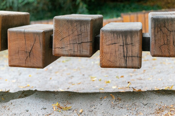 Unique wooden blocks create an intriguing play structure in an outdoor garden setting with soft sand underfoot