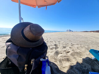 Conceptual photography of an umbrella on the beach with a hat and a backpack with Gibraltar in the...