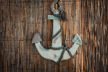 Rustic anchor adorned with frayed rope against a woven backdrop creates an inviting coastal atmosphere in this charming nautical decor