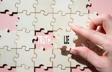 Truth or Lie symbol. Concept word Truth or Lie on wooden puzzle. Businessman hand. Beautiful pink...