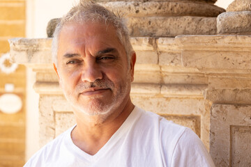 A man between 55 and 60 years old looking at the camera with a cheerful and complicit expression.