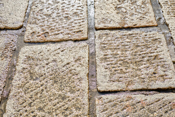 Wet stone pavement glistening in sunlight, showing texture and wear from weather and foot traffic.