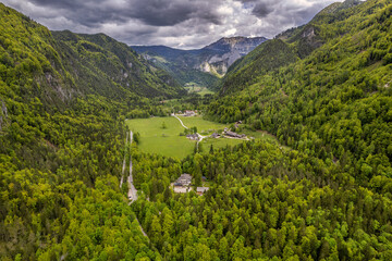 Aerial view of green valley and village in forested mountains
