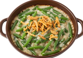 Overhead view of green bean casserole with fried onions in a brown ceramic dish on white surface