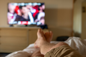 Selective focus on propped up feet with a blurred basketball game on the TV