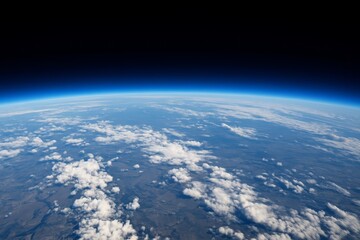 Fototapeta premium Stunning high-altitude view of Earth's atmosphere meeting outer space. White clouds drift above the curved planet surface.