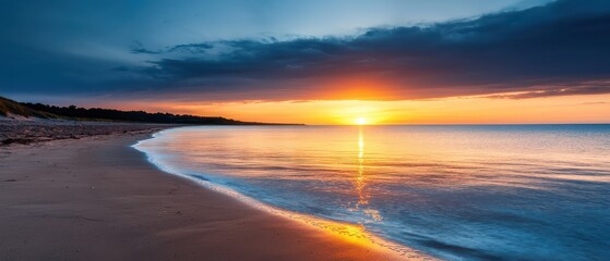 A tranquil beach at sunset with calm waves, a glowing sky, and the sun's reflection on the water near a sandy shore.