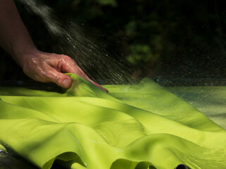 Hand pressing down on green fabric being sprayed with water