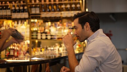 Profile closeup of smiling smart man in white shirt drinking cocktail in Old fashioned of special party beverage vibrant at nightclub on Friday meeting night time at luxurious counter bar. Vinosity.