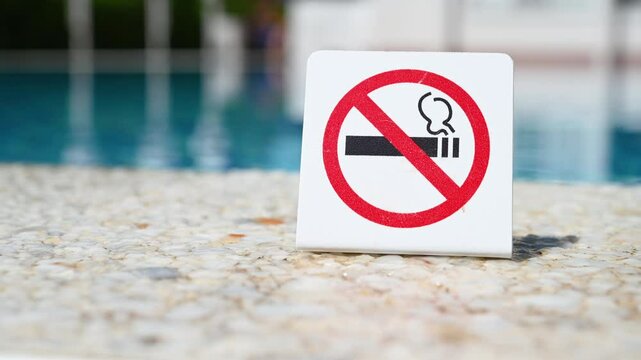 Attention, do not smoke. No smoking sign. Smoking is prohibited in public places. Prohibitory sign near blue water in the swimming pool