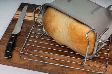Freshly Baked White Bread Cooling in a Pan on Wooden Cutting Board