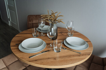 A beautifully crafted wooden table adorned with plates, utensils, and glasses set neatly on top, inviting everyone to gather around for a delightful meal and enjoyable conversation