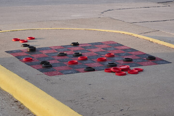 A large scale checkerboard game outside.