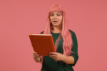 a woman in a green dress with pink hair and a pink book in her hands
