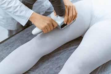 Therapist performing LPG vacuum roller massage treatment on the legs of a client in a white bodysuit, at a beauty spa.
