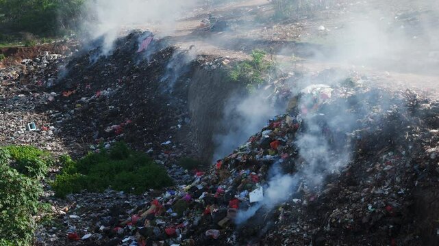 Burning trash in dump, plastic pollution, industry drone view in Bali.