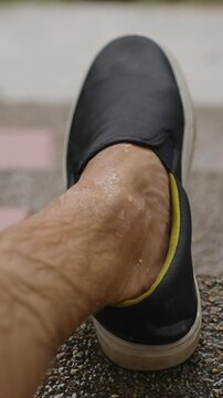 Vertical video. Man&rsquo;s Wet Foot Wearing Black Shoe Resting on Rainy Steps During Tropical Downpour in Slow Motion, Contemplative Mood Concept