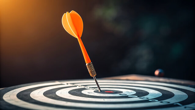 Photo of an orange dart perfectly hits the bullseye on a dartboard, symbolizing the achievement of a precise goal and ultimate success in a focused endeavor