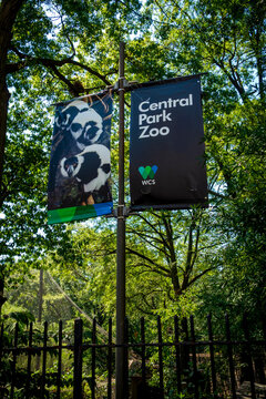 New York, NY - US - Jul 6 2025 Two banners hang from a pole, one reading "Central Park Zoo" with the WCS (Wildlife Conservation Society) logo, highlighting the organization that runs the zoo.