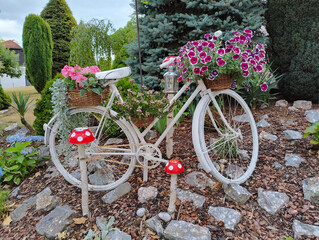 A white bicycle with a basket full of flowers on the back of it