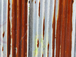 A close up of a rusted metal fence with peeling paint on it
