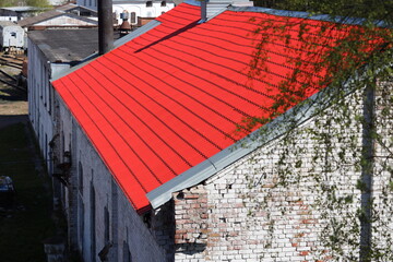 Image of a red metal roof on top of a brick building, great for use in urban or industrial settings