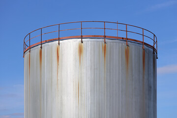 A large metal tank sits on top of a green field, with minimal background distractions