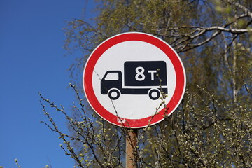 A roadside sign featuring a red and white design with an image of a truck, used for directional...