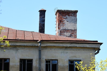 A weathered brick building with a functional chimney and rusted roof, great for rural or rustic scenes