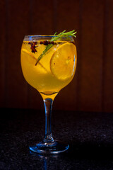 A beautifully presented cocktail featuring orange slices, rosemary, and vibrant colors.