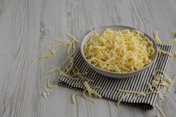 Organic Shredded Mozzarella Cheese in a Bowl, side view. Copy space.