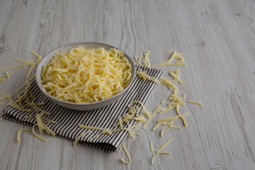 Organic Shredded Mozzarella Cheese in a Bowl, side view. Copy space.