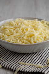 Organic Shredded Mozzarella Cheese in a Bowl, side view. Close-up.