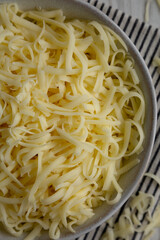 Organic Shredded Mozzarella Cheese in a Bowl, top view. Close-up.