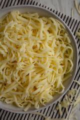 Organic Shredded Mozzarella Cheese in a Bowl, top view. Close-up.